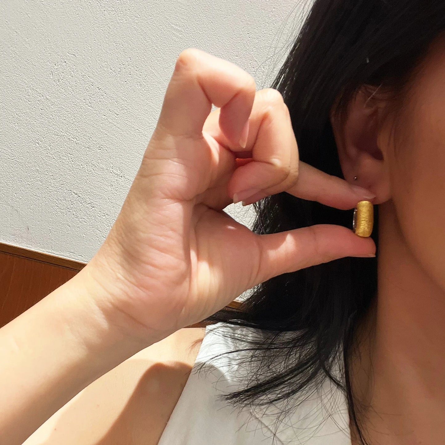 Minimalist luxury huggie earrings worn on ear with two-tone gold and silver finish