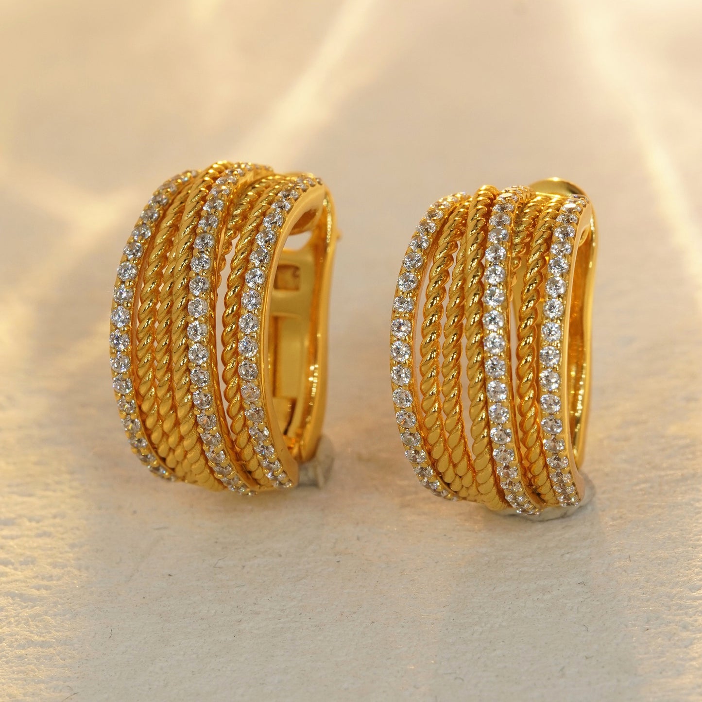 18K gold plated CZ huggie hoop earrings on beige background