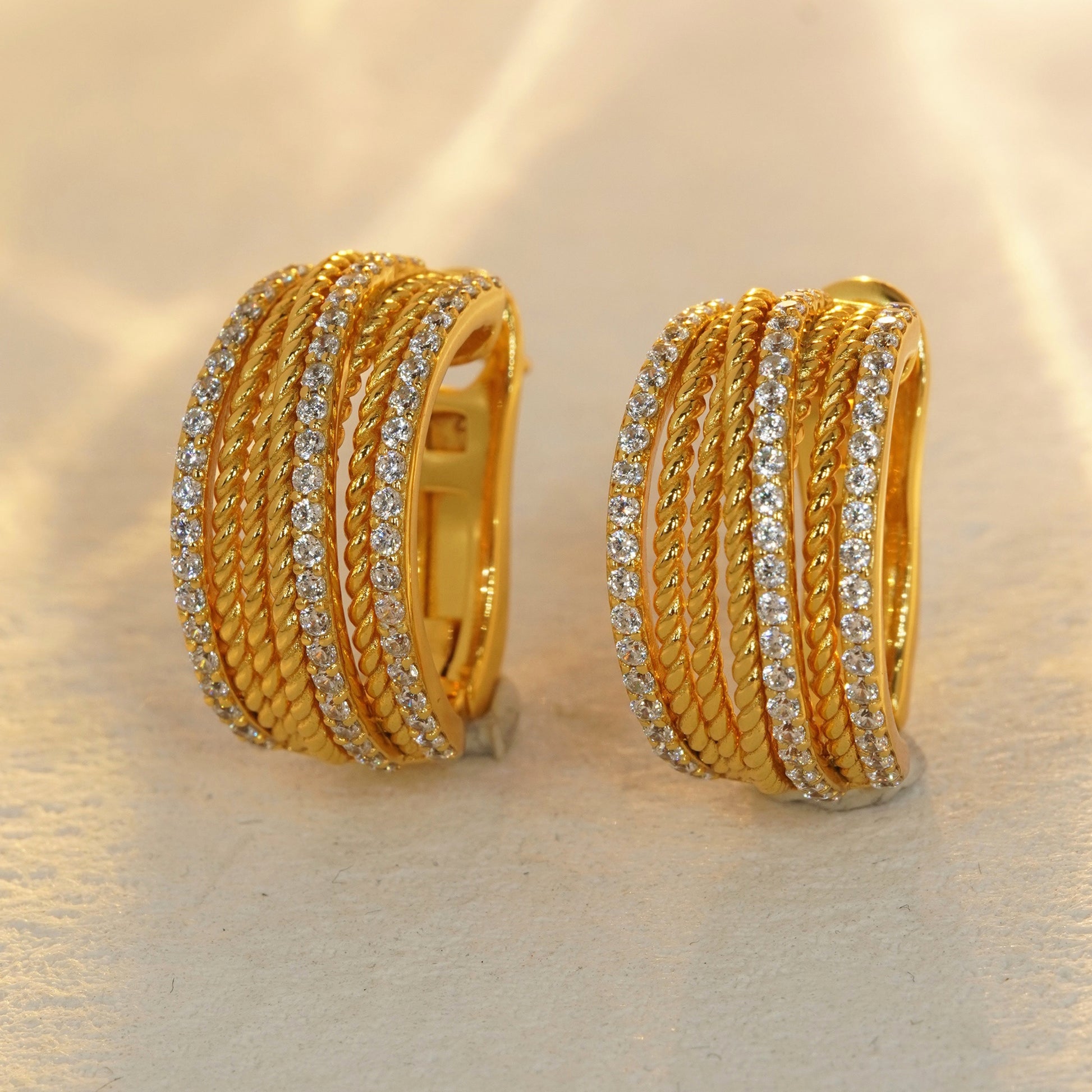 18K gold plated CZ huggie hoop earrings on beige background