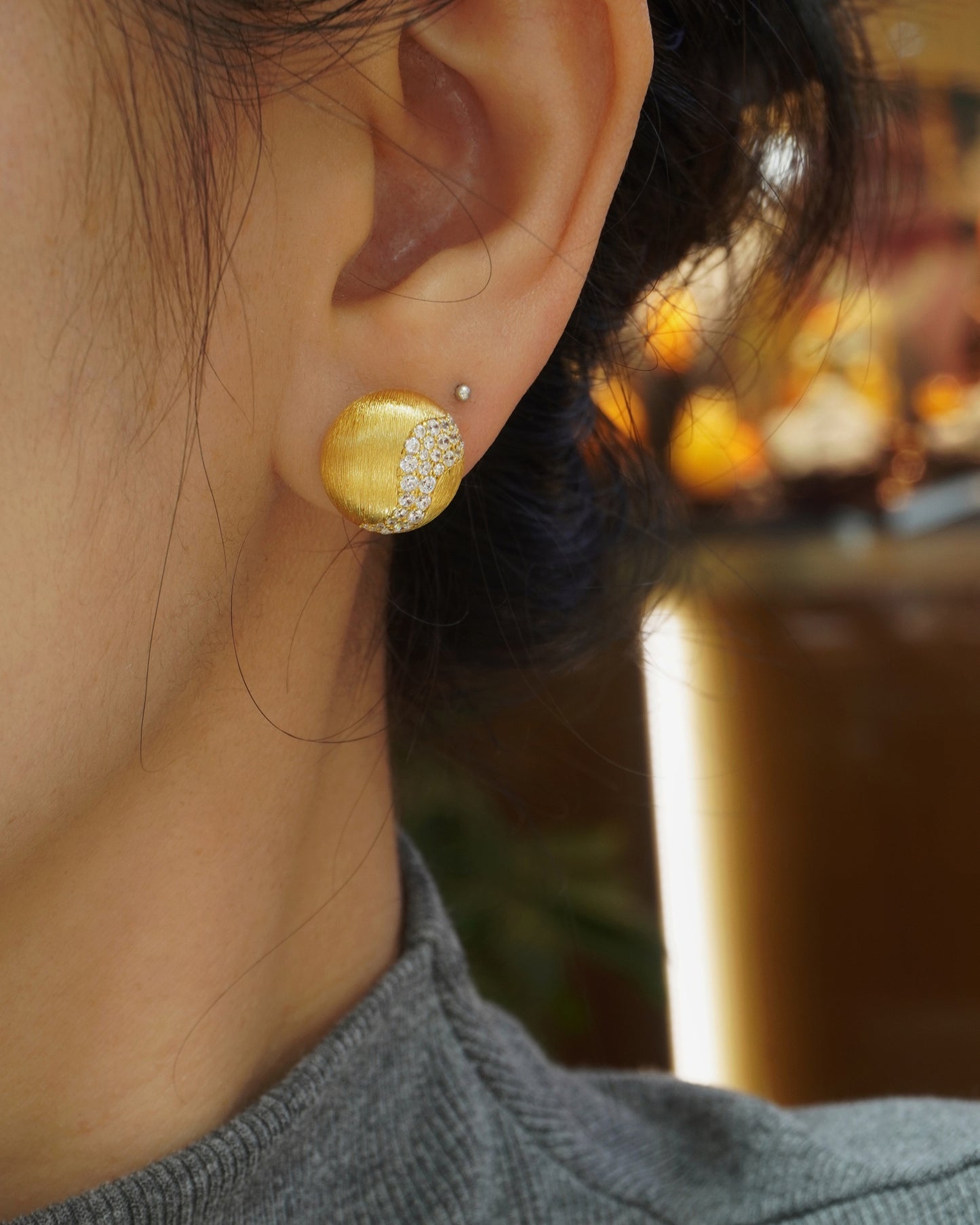 woman wearing minimalist brushed gold CZ stud earrings with elegant modern style