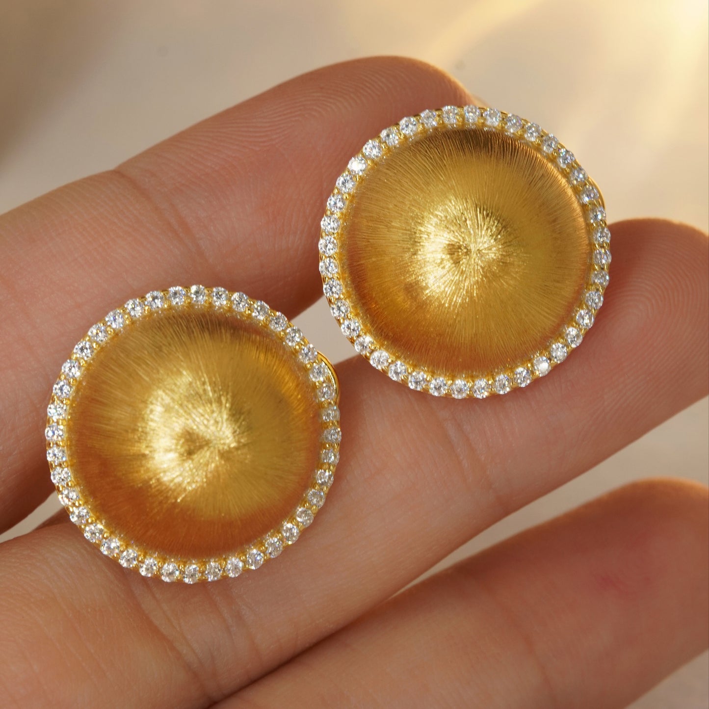 close up of luxury brushed gold dome earrings with cubic zirconia halo design