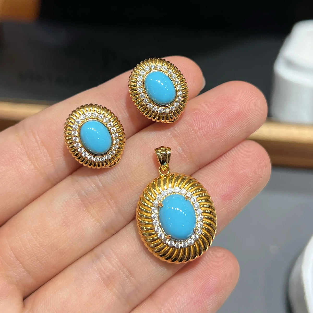 Close-up scale view of created turquoise earrings and pendant set
