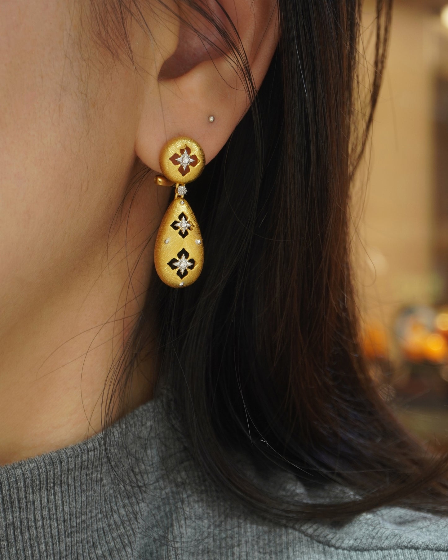 Woman wearing elegant brushed gold floral teardrop earrings