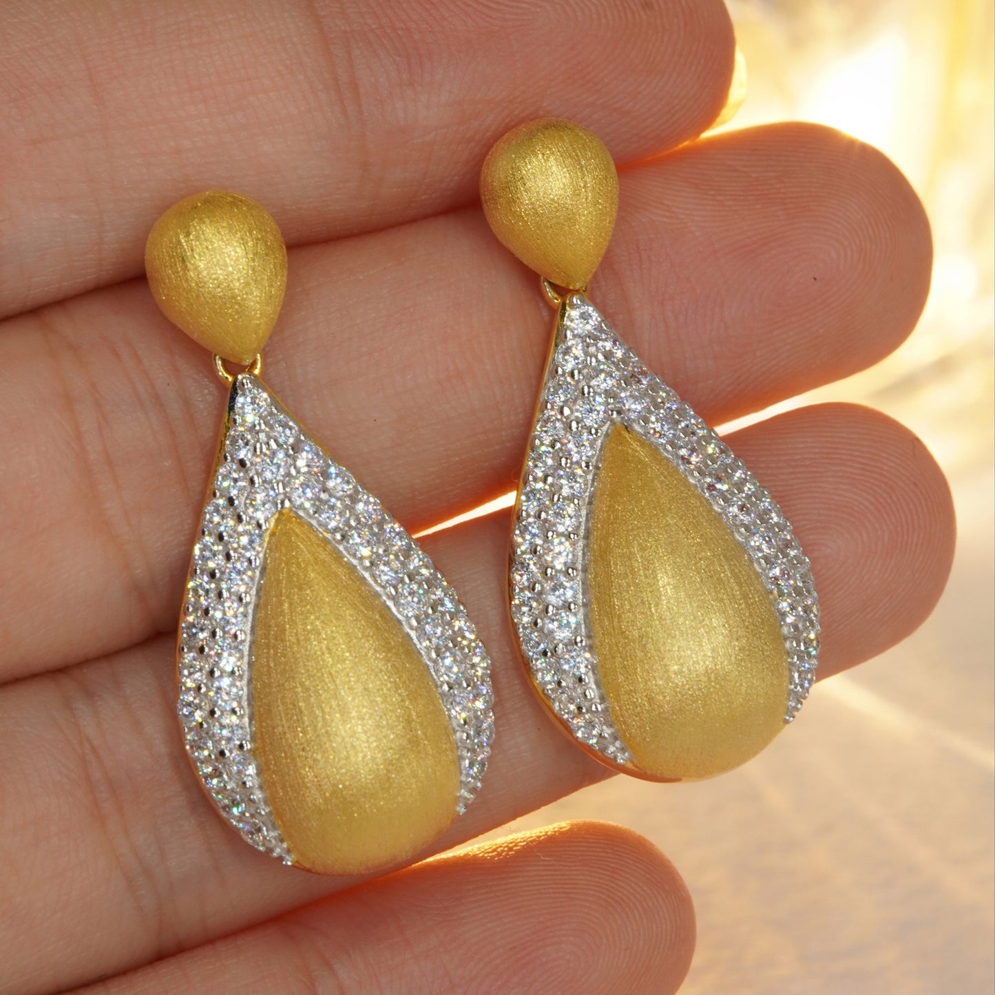 close up of luxury gold teardrop earrings with CZ gemstone details