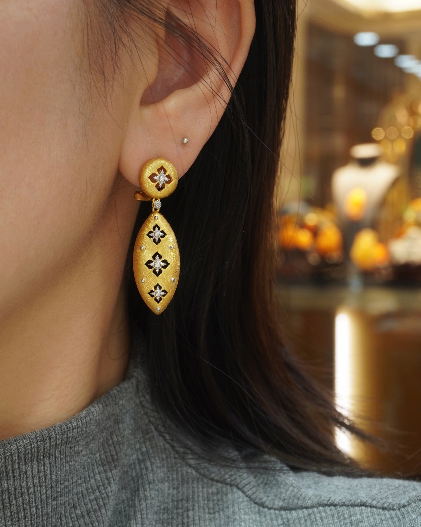 Woman wearing elegant brushed gold floral teardrop drop earrings