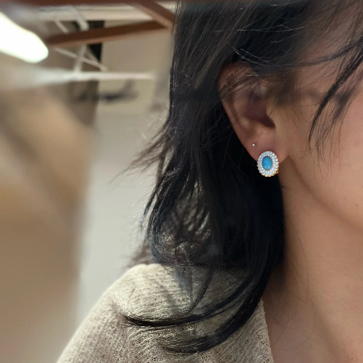 Model wearing an Azure Celestia pierced created turquoise halo earring