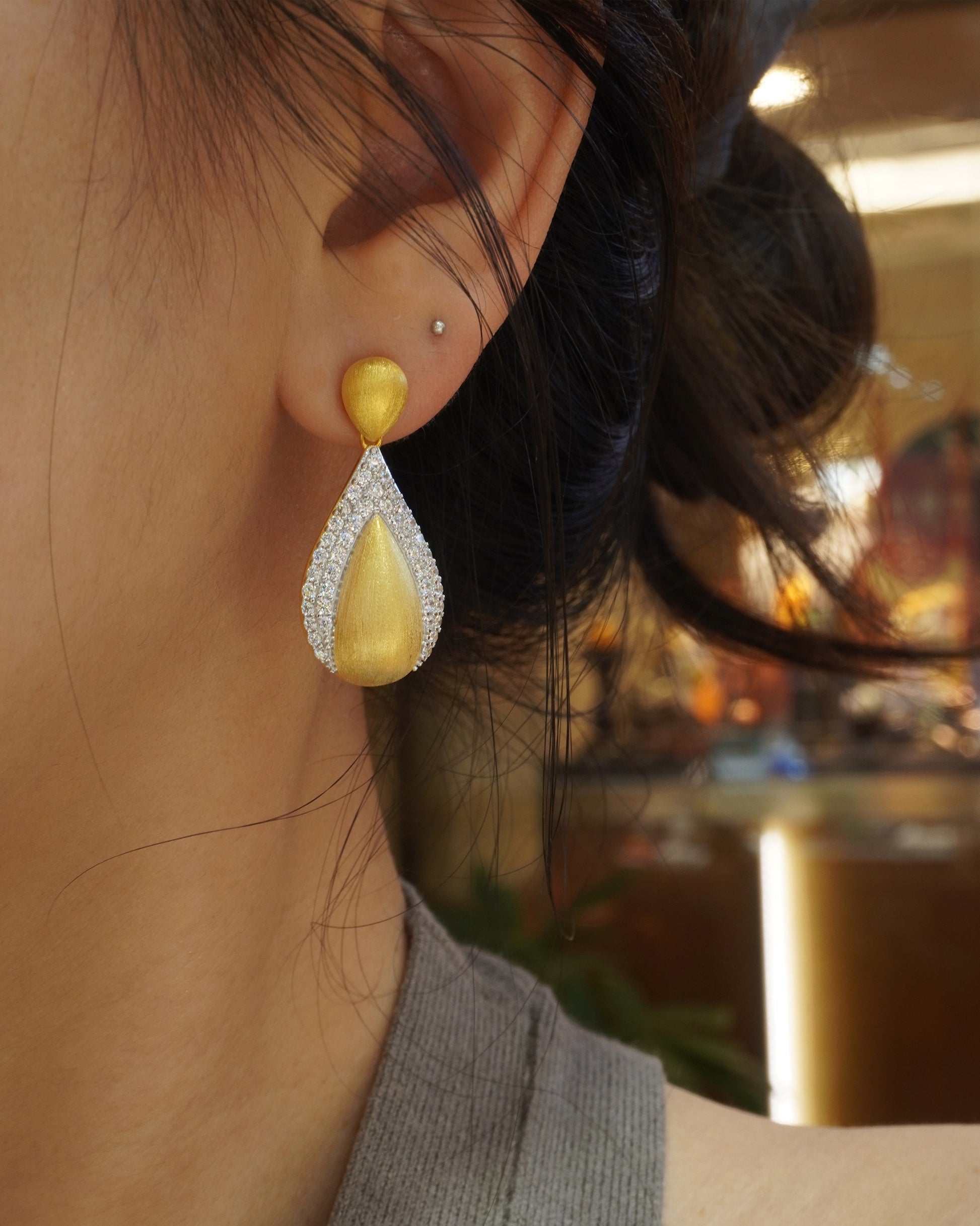 woman wearing elegant brushed gold teardrop CZ earrings