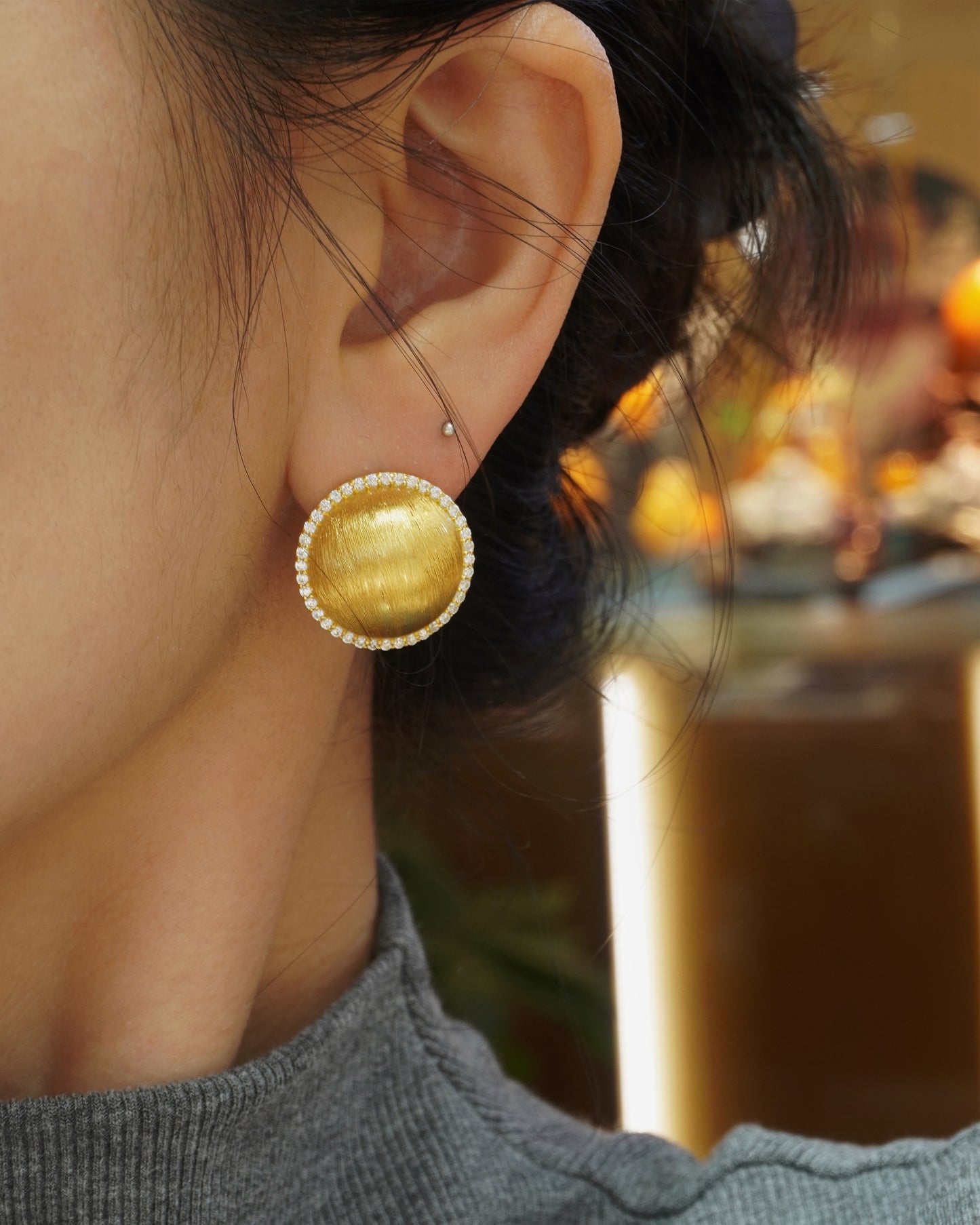 woman wearing elegant brushed gold round CZ halo stud earrings