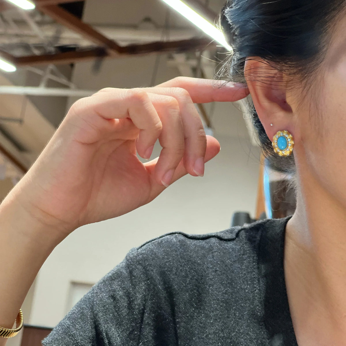 Model wearing the gilded oval created turquoise pierced stud earring
