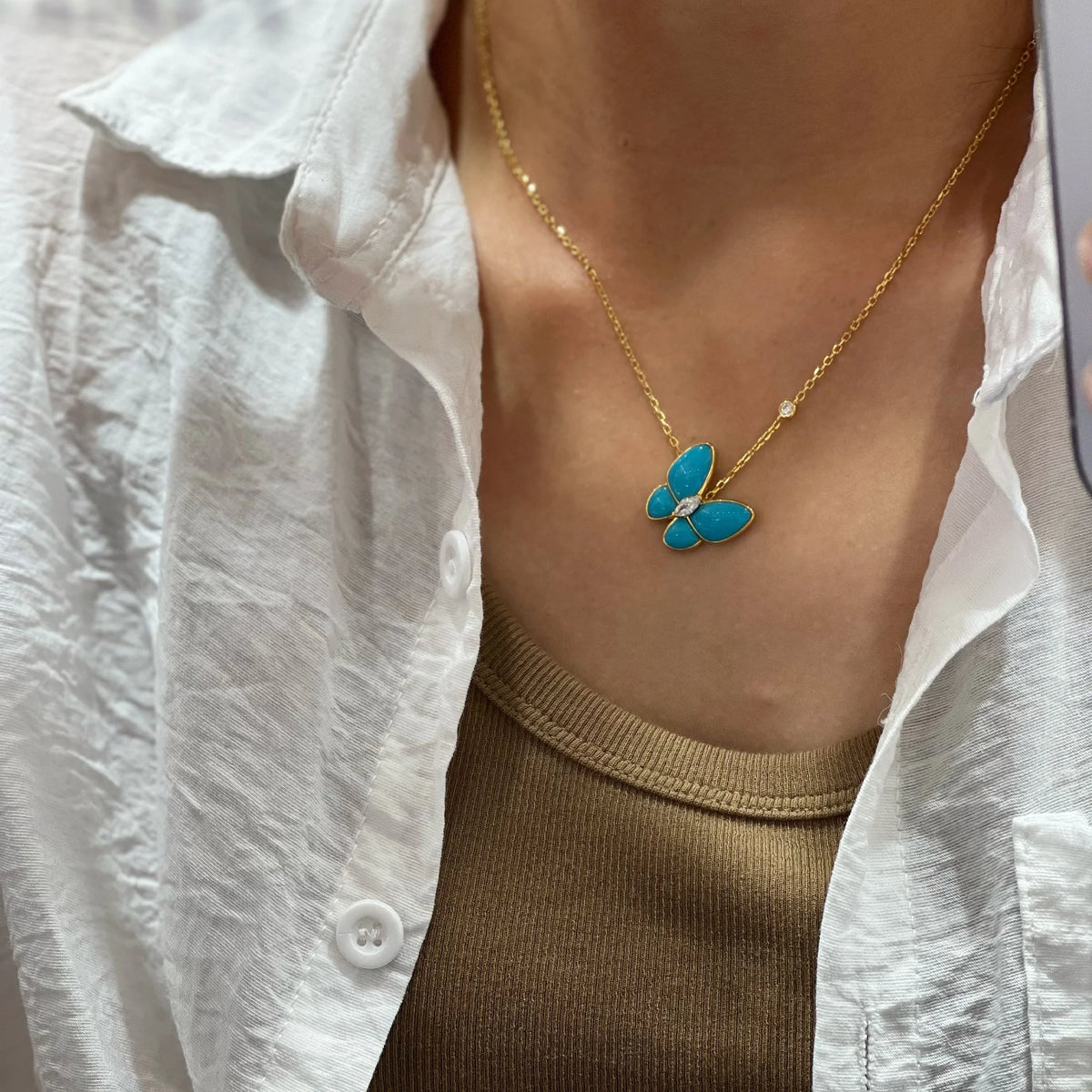 Gold created turquoise butterfly necklace worn by a model