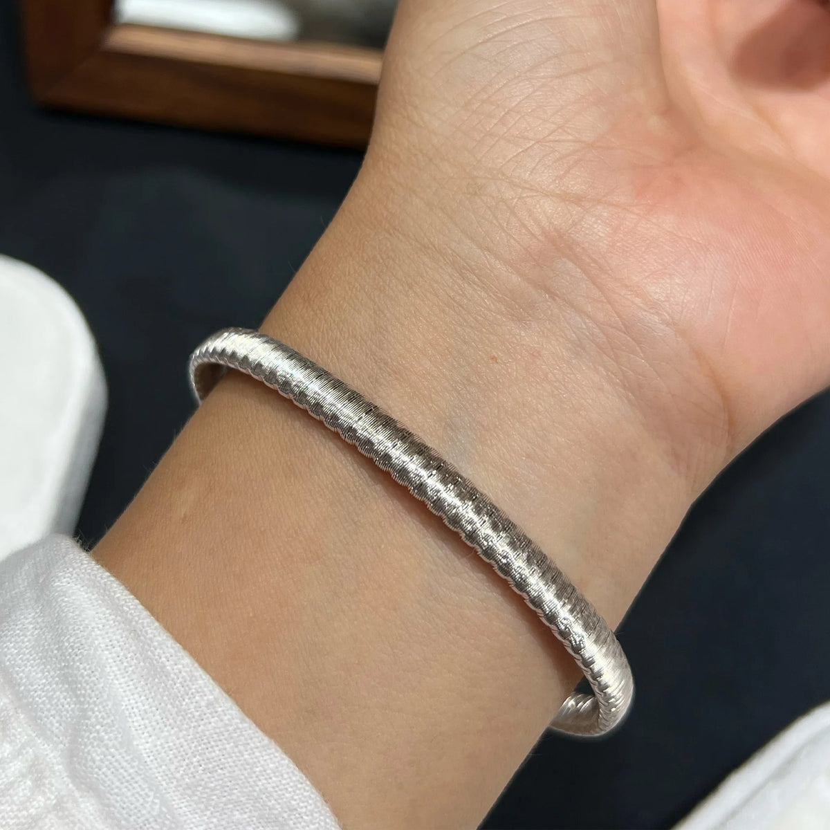 Silver brushed open cuff bracelet worn on the wrist