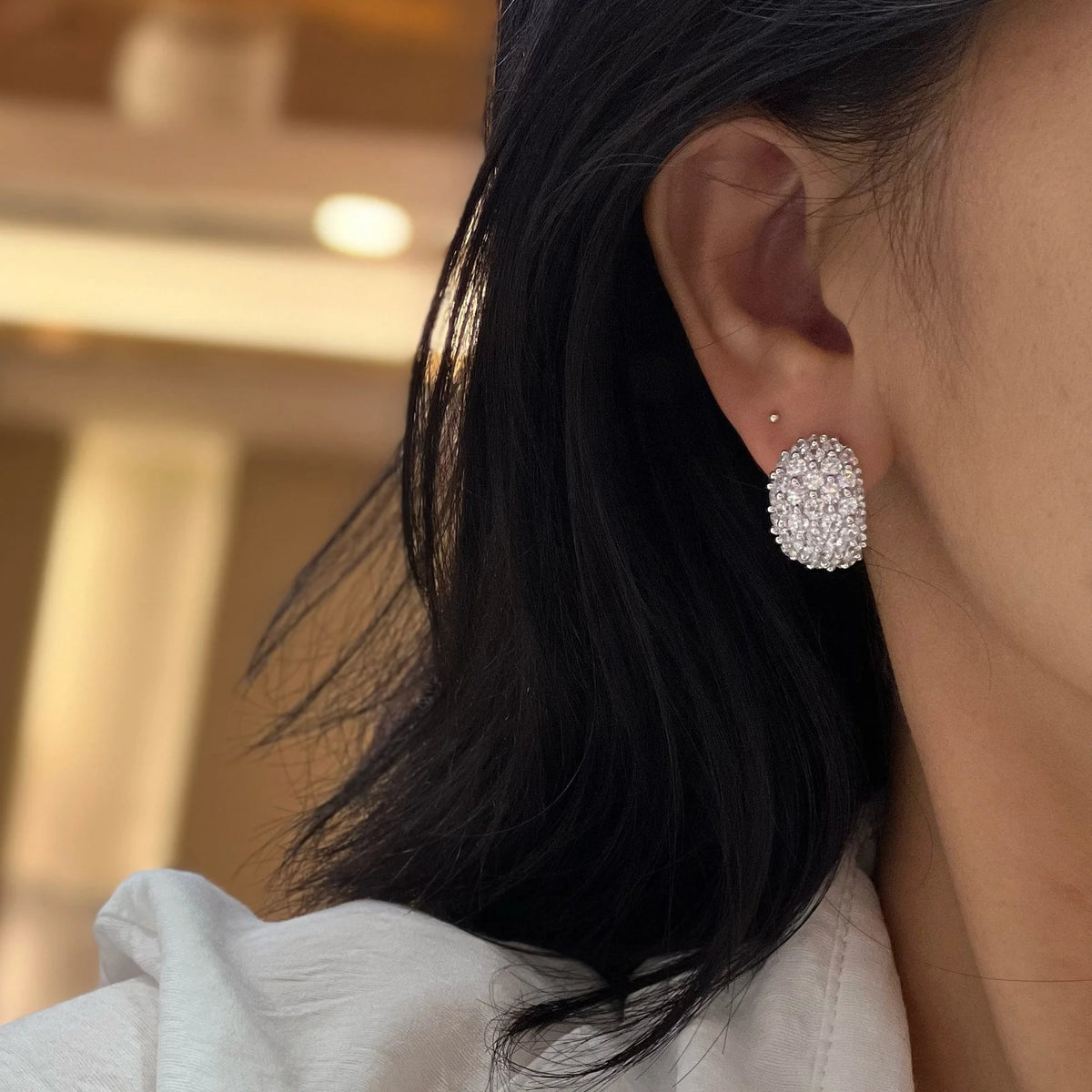 Clear pavé cubic zirconia wide clip-on earrings worn on ear