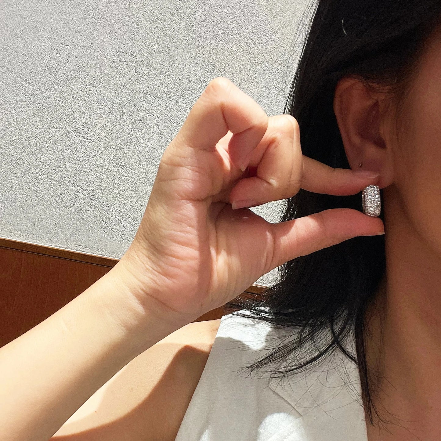 Minimalist luxury huggie earrings worn on ear with two-tone gold and silver finish