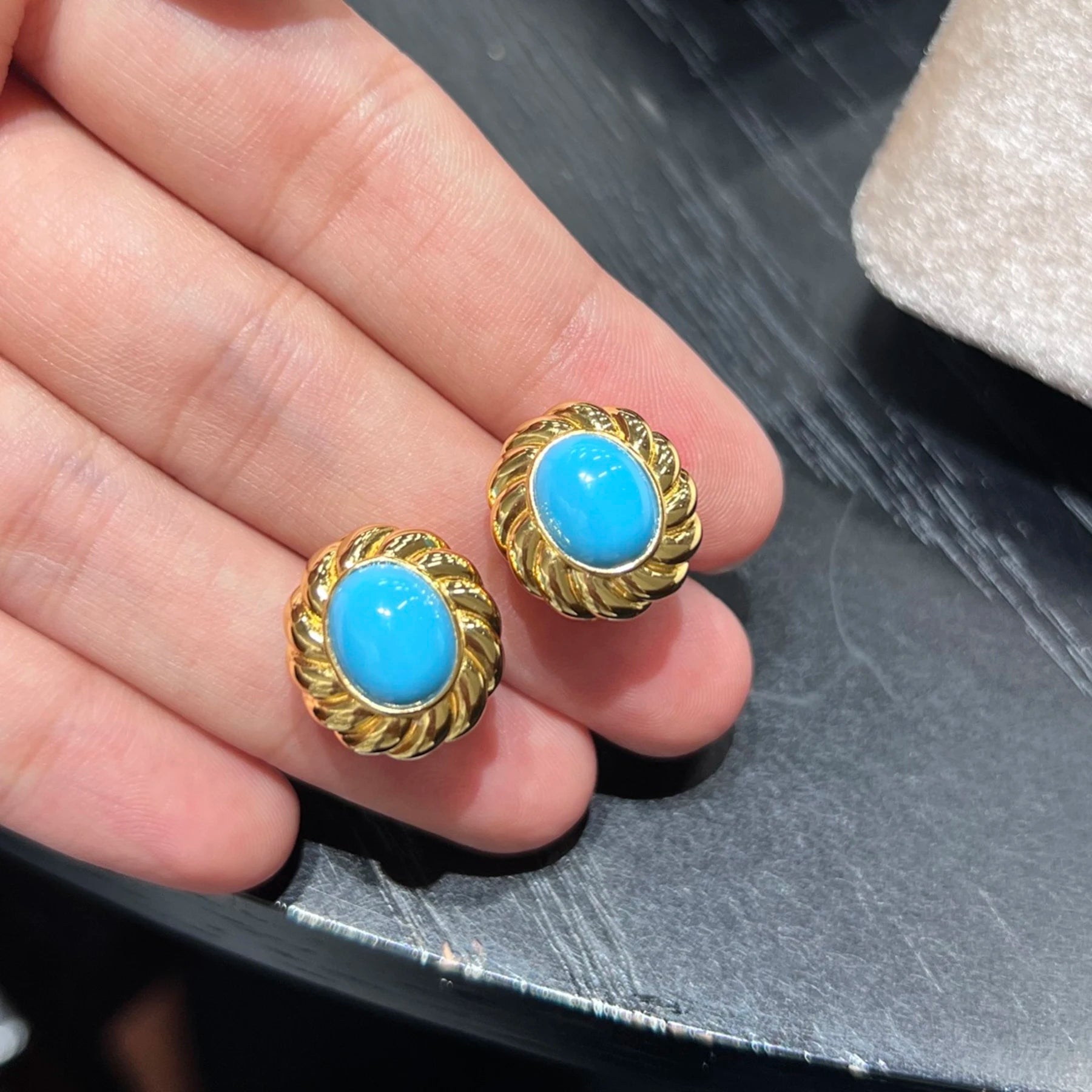 close up of blue created turquoise cabochon earrings with twisted gold frame