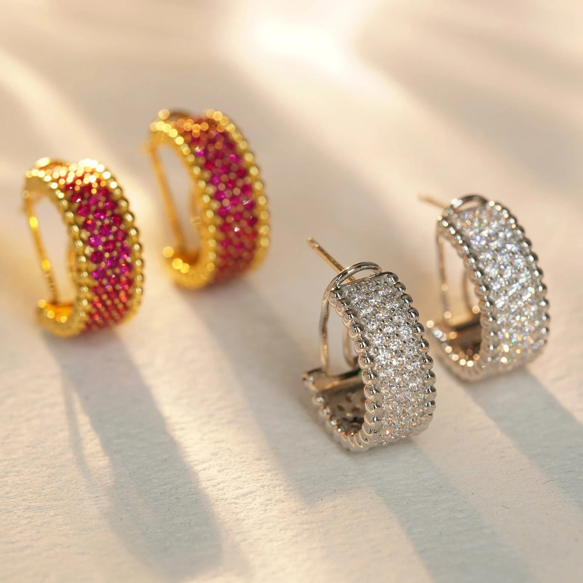 Silver clear CZ and gold red CZ beaded-edge hoop earrings, angled view