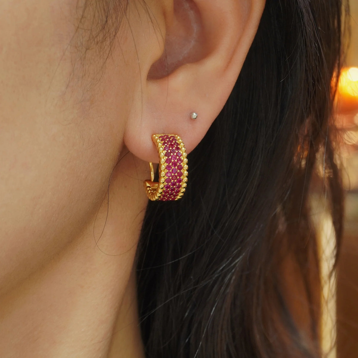 Gold red CZ beaded-edge hoop earring worn on ear
