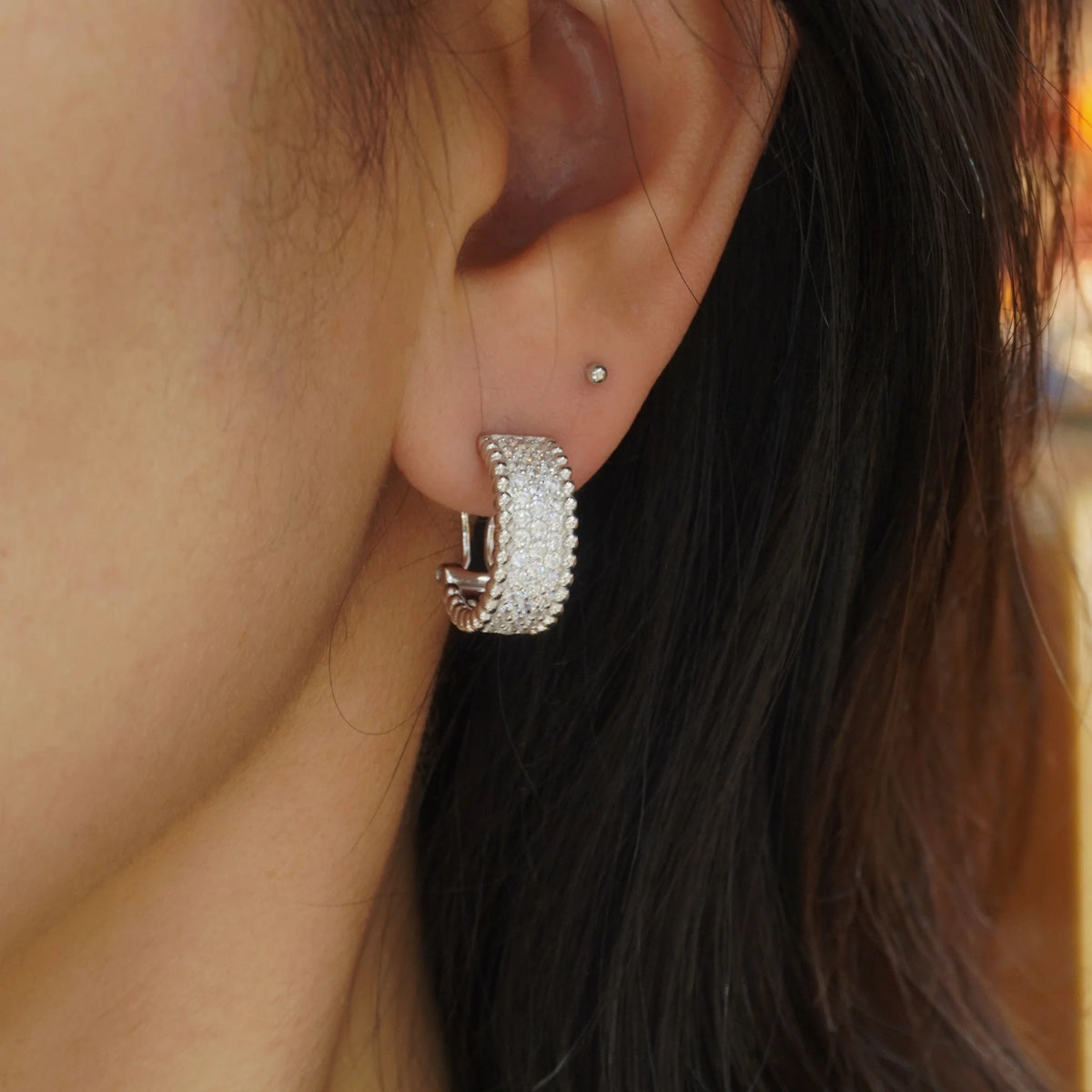 Silver clear CZ beaded-edge hoop earring worn on ear