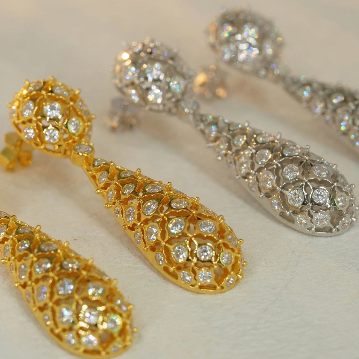 Openwork floral pavé CZ drop earrings in gold and silver, close-up detail