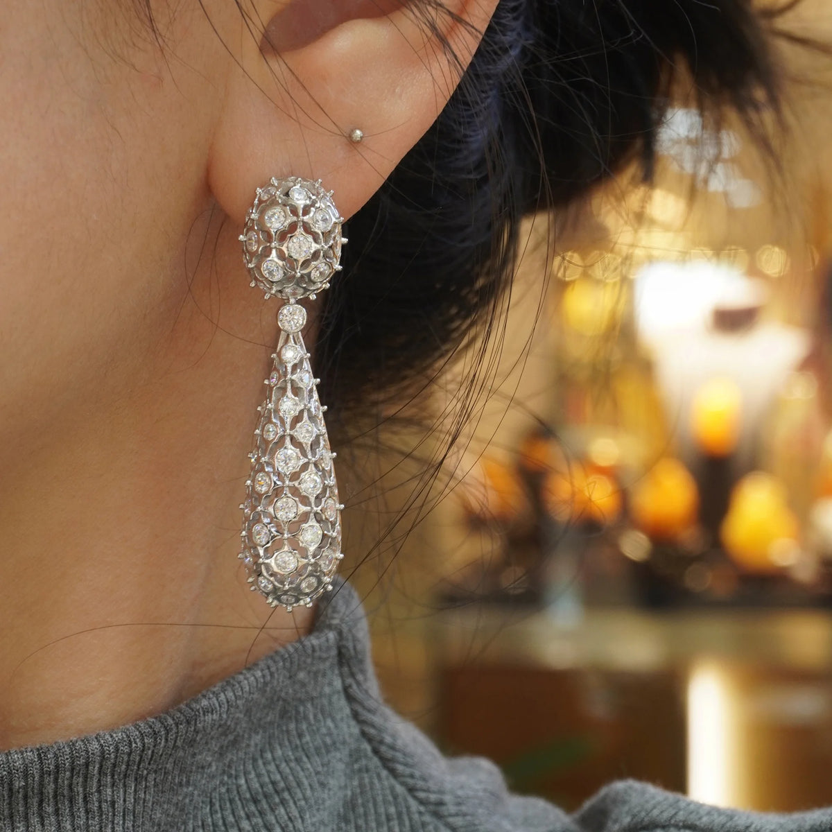 Silver openwork floral pavé CZ drop earring worn on ear