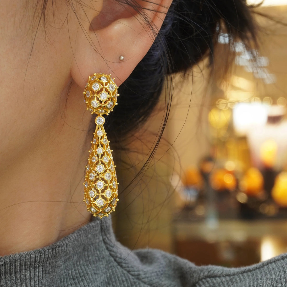 Gold openwork floral pavé CZ drop earring worn on ear