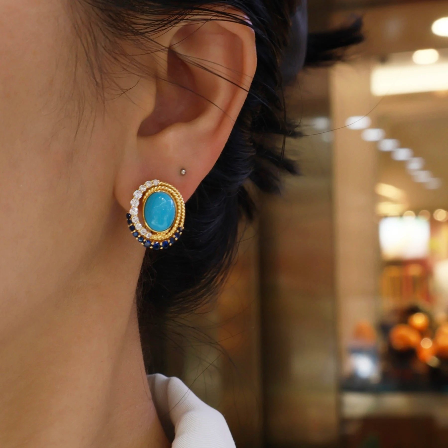 woman wearing royal blue turquoise gold statement stud earrings